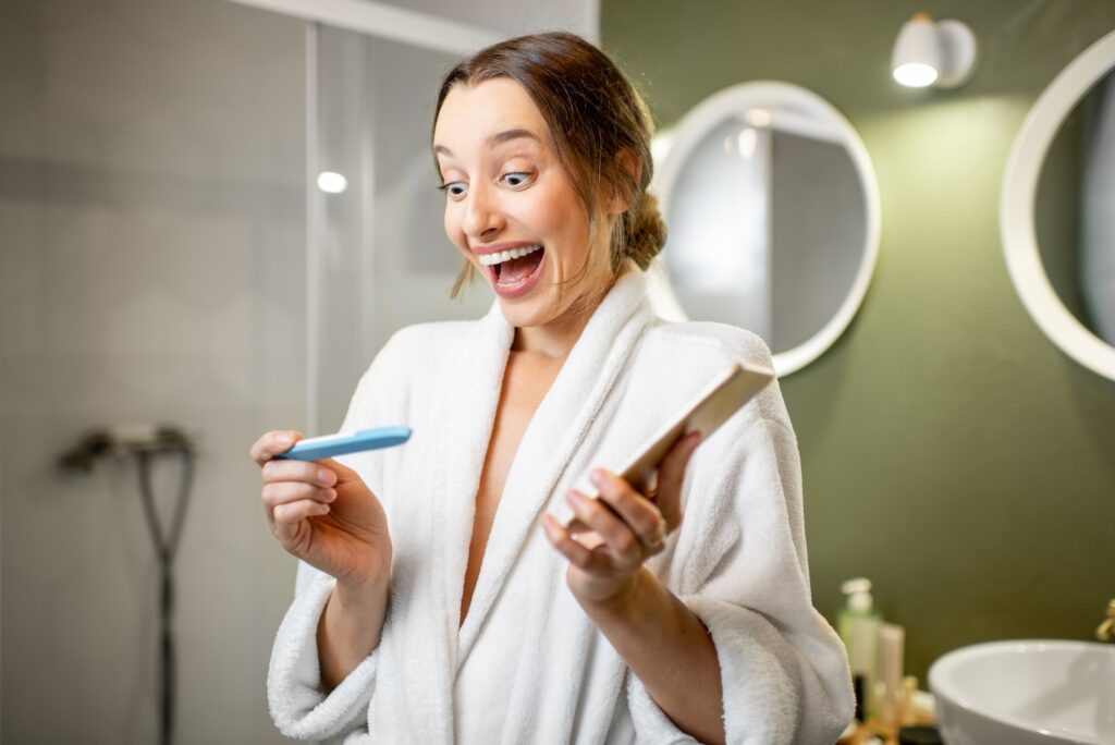 Happy woman with pregnancy test in the bathroom